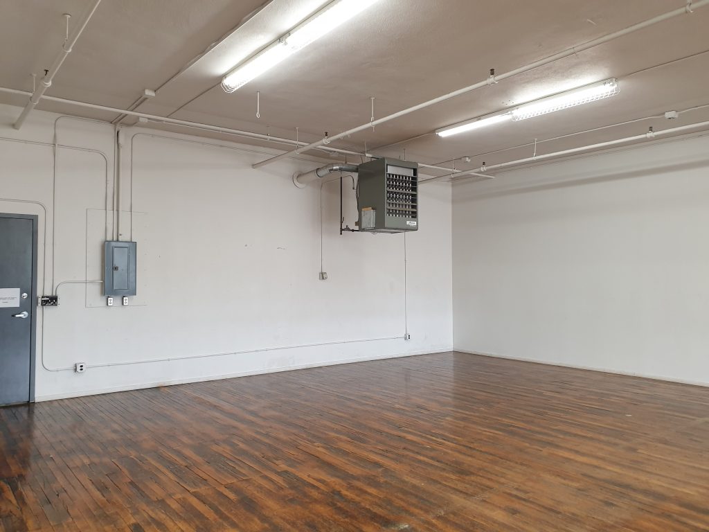 An oblique view of the Movo dance space featuring a white wall and hardwood flooring